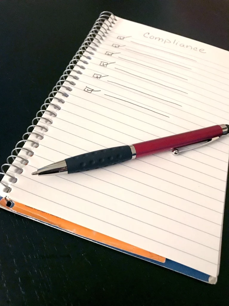 Checklist notebook titled “Compliance” with a pen, symbolising IEC and SANS UPS compliance, FSCA uptime requirements, and Riello UPS solutions from Standby Systems in South Africa.