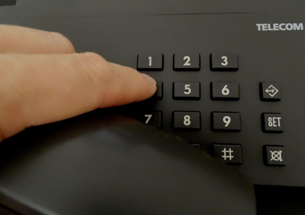 Close-up of a person dialing a telephone keypad, symbolizing contacting Standby Systems South Africa for Riello UPS support, service, and sales assistance.